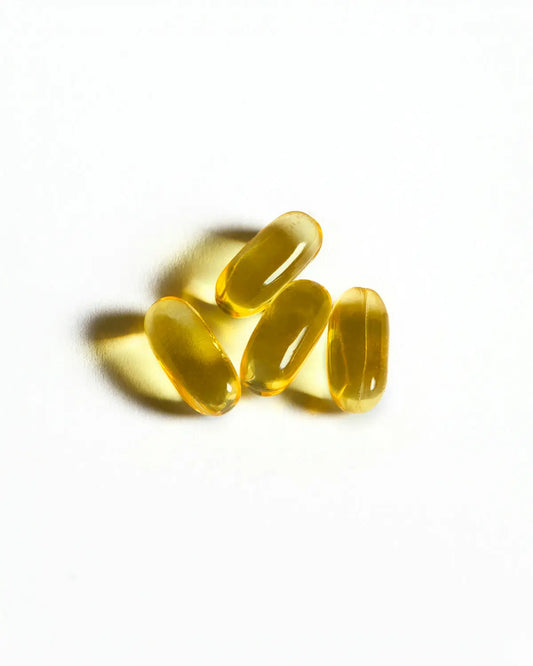 Four yellow capsules sit on a white surface.