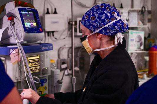 Medical professional in scrubs and mask operating equipment.