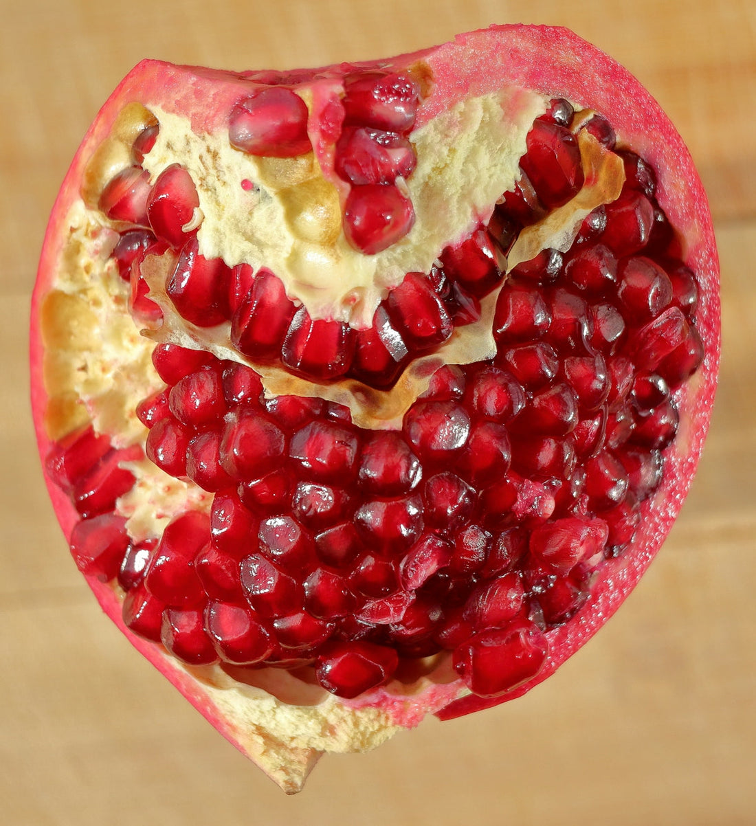 Natural antioxidant - A halved pomegranate with red seeds on a wooden surface